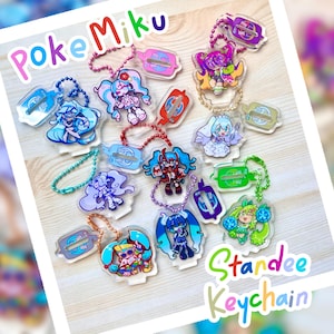 Könnte beinhalten: Eine Sammlung von Acryl-Standee-Schlüsselanhängern mit farbenfrohen Anime-Charakteren. Jeder Schlüsselanhänger hat ein einzigartiges Design und ist an einer Metallkette befestigt. Der Text "Poke Miku" und "Standee Keychain" sind sichtbar.