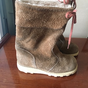 Peut inclure: Bottines en daim marron avec une semelle plateforme blanche et des lacets rouges. Les bottes ont une doublure en fourrure et un revers rabattable.