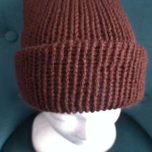 Puede incluir: Un gorro de punto marr&oacute;n con textura de canal&eacute;.