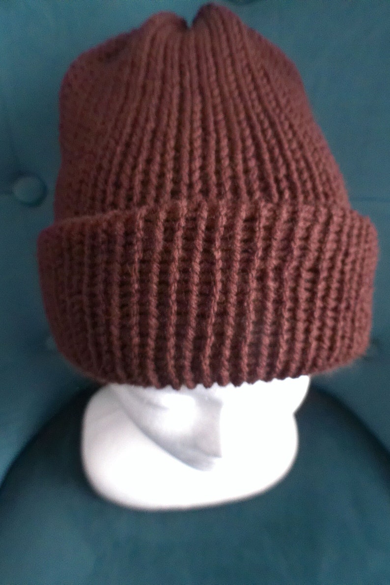 Puede incluir: Un gorro de punto marr&oacute;n con textura de canal&eacute;.