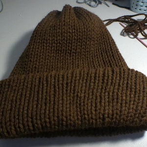 Puede incluir: Un gorro de punto marr&oacute;n con un borde doblado.