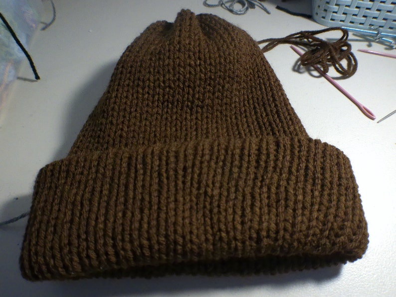 Puede incluir: Un gorro de punto marr&oacute;n con un borde doblado.