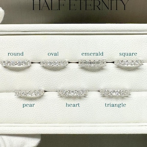 May include: A display of seven diamond rings with different stone shapes: round, oval, emerald, square, pear, heart, and triangle. The text "7 STONES HALF ETERNITY" is above the rings. The rings are displayed in a white box.