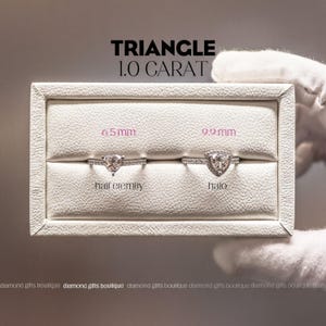 a hand holding a white jewelry box containing two diamond rings, with text above the box indicating the size of the diamonds.
