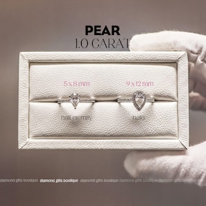two diamond engagement rings displayed in a white jewelry box, with a hand wearing white gloves holding the box.