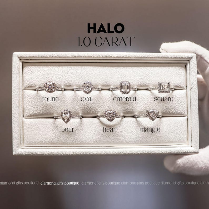A display case containing various diamond engagement rings, each with different shapes and designs, including round, oval, emerald, square, pear, heart, and triangle.