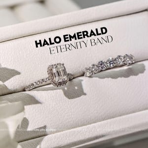 A close-up of two diamond engagement rings on a white surface, with the text "HALO EMERALD ETERNITY BAND" displayed above them.