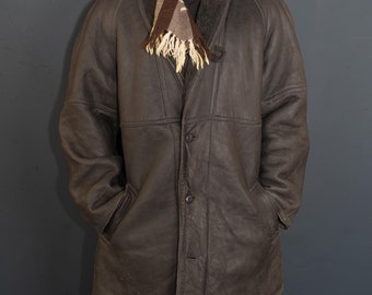 May include: A brown leather jacket with a shearling collar and a plaid scarf. The jacket has a button closure and pockets on the sides.