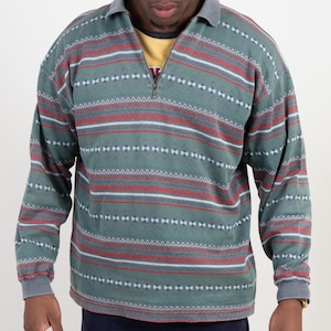 Könnte beinhalten: Ein langärmeliges Pullover-Shirt in gedämpftem Salbeigrün mit einem halben Reißverschluss am Kragen und einem horizontalen Muster aus dünnen roten, weißen und dunkelgrünen Streifen mit geometrischen Akzenten sowie grauem Kragen und Bündchen.