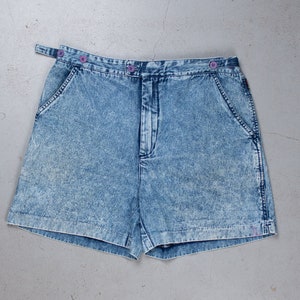 Pode incluir: Shorts de ganga azul claro com um visual desbotado e fecho de botão. Os shorts têm passadores de cinto e dois bolsos na frente.