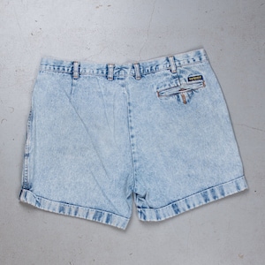 Pode incluir: Shorts de ganga azul claro com bainha dobrada e um pequeno bolso na parte de trás. Os shorts têm fecho de botão e zíper.