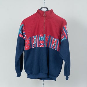 May include: A red, blue, and green patterned fleece pullover with a half-zip closure.