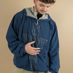 Peut inclure: Une veste à capuche bleue avec une fermeture éclair et un grand imprimé graphique du mot "HOLLYWOOD" dans une police stylisée.