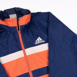 May include: A blue, orange and white striped jacket with a white Adidas logo on the chest.