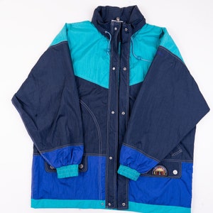 May include: A blue and teal color block jacket with a zipper and snap closure. The jacket has a hood and a logo patch on the lower right side that says "Killtec".