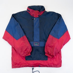 Può includere: Una giacca a vento blu e rossa con cerniera e cappuccio con coulisse. La giacca ha un logo sul davanti che dice "Land's End" e una piccola tasca sul petto.