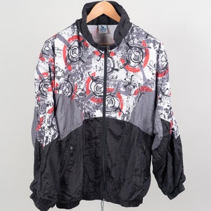 May include: A black, grey, and red patterned jacket with a zip closure. The jacket has a stand-up collar and long sleeves.