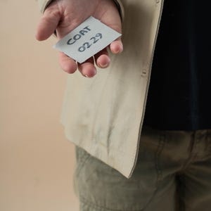 May include: A person holding a white card with the text "COAT 0229" written on it.