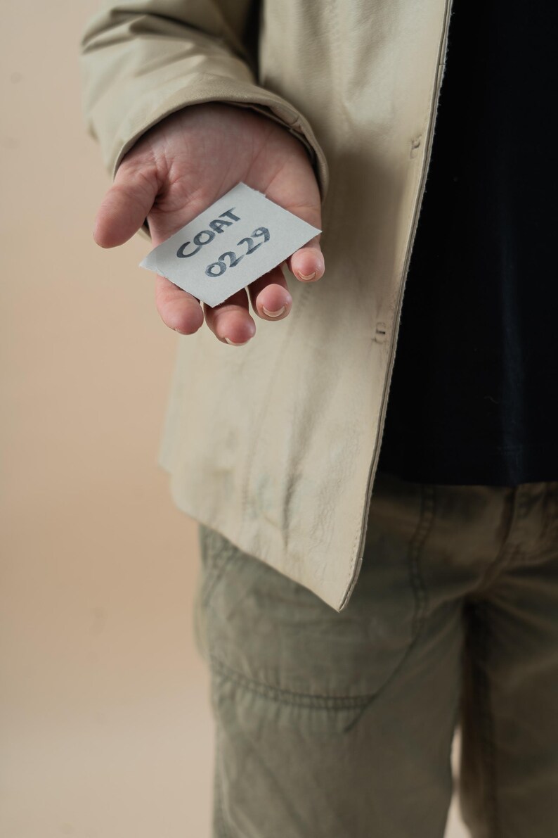 May include: A person holding a white card with the text "COAT 0229" written on it.