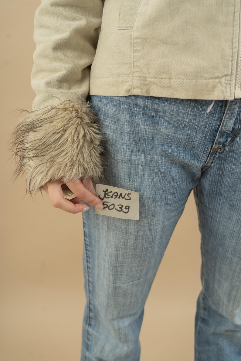 Może przedstawiać: Jasne niebieskie dżinsy z białą karteczką przyklejoną z przodu, na kt&oacute;rej napisano "Jeans 5039".