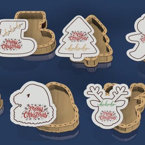 Puede incluir: Recortes de madera con temática navideña en varias formas, incluyendo un calcetín, un árbol de Navidad, un hombre de jengibre, un gorro de Papá Noel y un reno. Cada recorte tiene una base de madera a juego y el texto "Merry Christmas" y "hohoho".