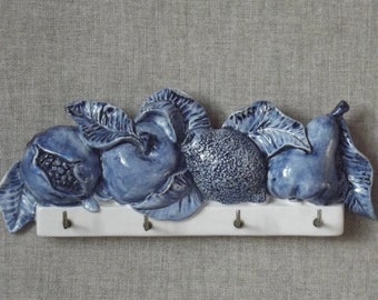 Key hanger/tidy. Italian ceramic plaque decorated with pomegranate, apple lemon and pear,4 metal hooks, overall blue glaze.