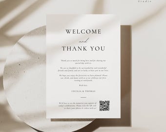May include: A minimalist wedding welcome sign with the text "WELCOME and THANK YOU" in elegant black font. The sign includes a heartfelt message and a QR code for sharing photos and videos. The sign is on a neutral background.