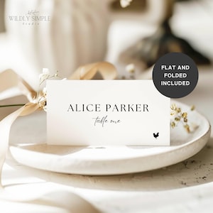 Puede incluir: Una tarjeta de sitio blanca con el nombre "Alice Parker" y "table one" impresos en negro. Un pequeño gráfico de gallo está en la parte inferior derecha. La tarjeta está sobre un plato blanco con una cinta y flores en el fondo. El texto "FLAT AND FOLDED INCLUDED" está en un círculo negro.