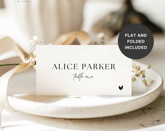 May include: A white place card with the name "Alice Parker" and "table one" printed in black. A small rooster graphic is at the bottom right. The card is on a white plate with a ribbon and flowers in the background. The text "FLAT AND FOLDED INCLUDED" is in a black circle.