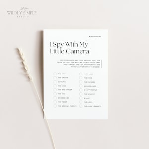 May include: A white card with the text "I Spy With My Little Camera." includes a list of wedding-related items to photograph. The card has a minimalist design with the words "Wildly Simple Studio" at the top.