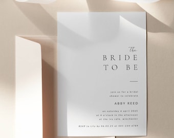 May include: A white card with black text announcing a bridal shower for Abby Reed on Saturday, April 6, 2025 at 4:00 PM at the Ivy Cafe in Winchester. The text also includes RSVP information.