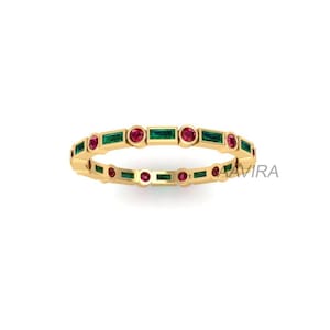 May include: A gold band ring with alternating emerald green and ruby red gemstones. The ring is set with rectangular emerald green stones and round ruby red stones.