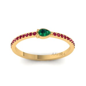 May include: A gold ring with a pear-shaped green gemstone and a band of small red gemstones.