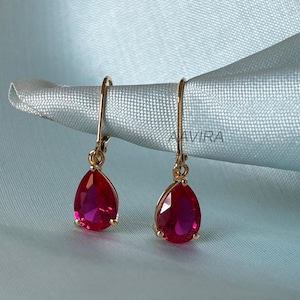 May include: A pair of gold earrings with teardrop-shaped red gemstones.