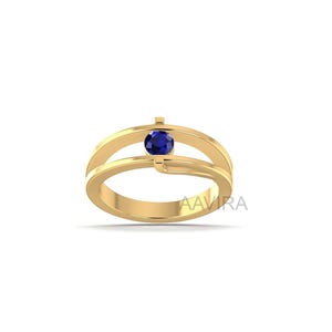 May include: A gold ring with a split band design, featuring a round, deep blue gemstone. The ring has a polished finish and the brand name "AAVIRA" is printed on the band.