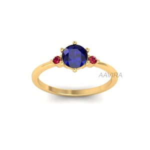 May include: A gold ring with a blue sapphire center stone and two smaller red ruby accent stones.