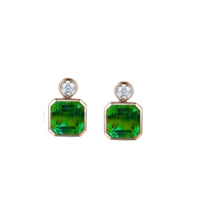 May include: A pair of gold earrings featuring a square green gemstone and a small round diamond accent.