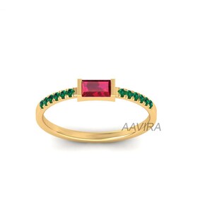 May include: A gold ring with a red rectangular gemstone and a band of green gemstones.