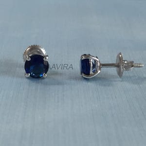 May include: A pair of silver stud earrings with round blue gemstones.