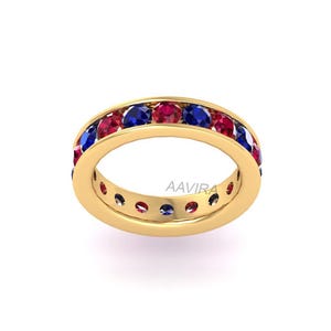 May include: A gold band ring with a row of alternating red and blue gemstones. The ring is set with a total of 12 gemstones.