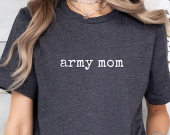 Könnte beinhalten: Dunkelgraues T-Shirt mit dem weißen Text "army mom". Das kurzärmelige Shirt hat einen Rundhalsausschnitt und ist aus einem weichen Stoff gefertigt. Der Stil des T-Shirts ist lässig.