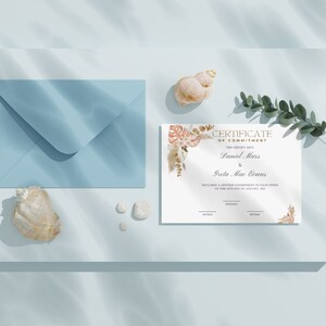 K&ouml;nnte beinhalten: Eine Verpflichtungsurkunde mit den Namen Daniel Mars und Greta Mae Evans, mit floralen Akzenten, liegt neben einem blauen Umschlag, Muscheln und kleinen wei&szlig;en Steinen. Die Urkunde liegt auf einer hellblauen Oberfl&auml;che.
