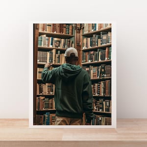 May include: A framed photograph of a person in a green hoodie and a white cap, reaching for a book on a shelf in a library. The shelves are filled with books of various sizes and colors, creating a warm, inviting atmosphere.