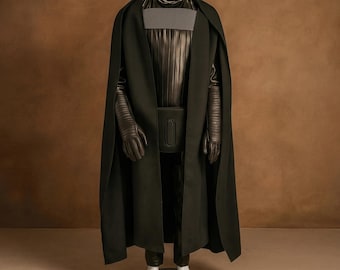 May include: A black costume with a long cape, gloves, and a chest piece. The costume has a belt with a rectangular buckle. The sleeves are ribbed, and the cape is draped over the shoulders. The costume is dark and imposing.