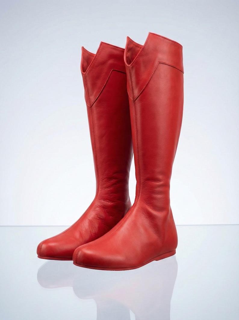 K&ouml;nnte beinhalten: Ein Paar hohe, rote Lederstiefel. Die Stiefel haben ein kniehohes Design mit spitzer Zehenpartie und einem einzigartigen, eckigen Oberteil. Die Stiefel sind aus glattem, gl&auml;nzendem Leder und vor wei&szlig;em Hintergrund.