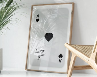 May include: A framed print of an ace of spades playing card with a palm tree silhouette overlay. The text "lucky you" is printed on the card.