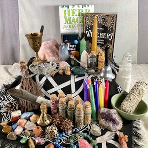 Puede incluir: Un paño de pentagrama negro con varios cristales, hierbas, velas y otros artículos de brujería, incluyendo un libro titulado "Witchery: Trace the Within" y un libro titulado "Herb Magic for Beginners: Down-to-Earth Enchantments".