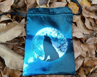 Puede incluir: Una bolsa de cordón de satén azul con un lobo aullando a la luna. La luna es blanca con un fondo de cielo estrellado azul y blanco.