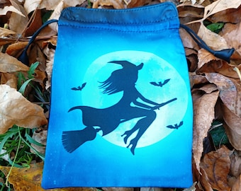 Puede incluir: Una bolsa de cordón azul con una silueta negra de una bruja volando en una escoba frente a una luna llena. La luna tiene un fondo blanco y está rodeada de murciélagos.