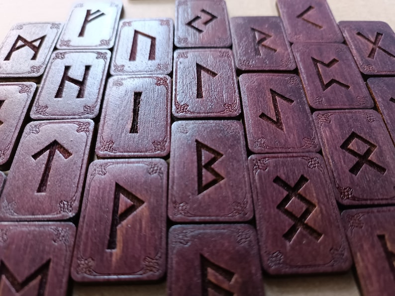 May include: A set of wooden runes with a dark purple stain. Each rune is engraved with a different symbol. The runes are arranged in a staggered pattern.